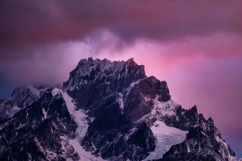 a large mountain covered in snow under a cloudy sky