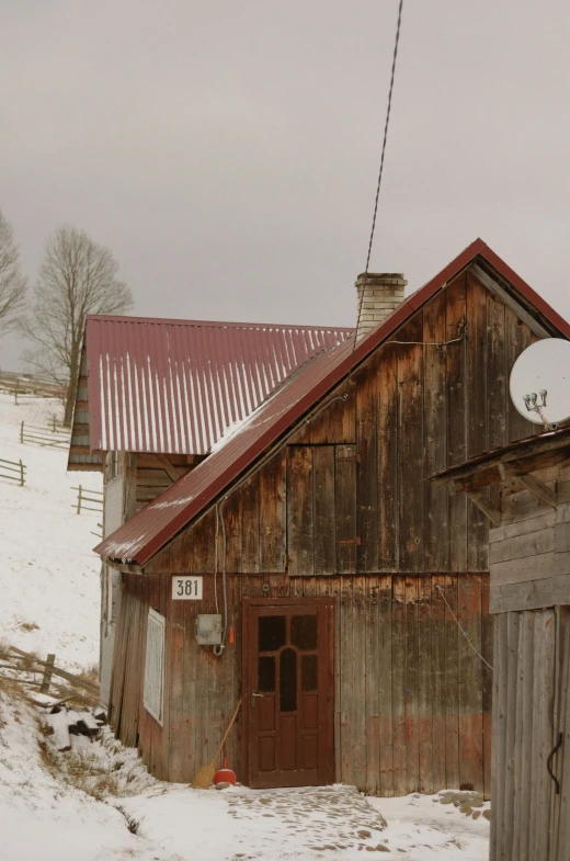 a red roofed building sitting next to a small wooden barn