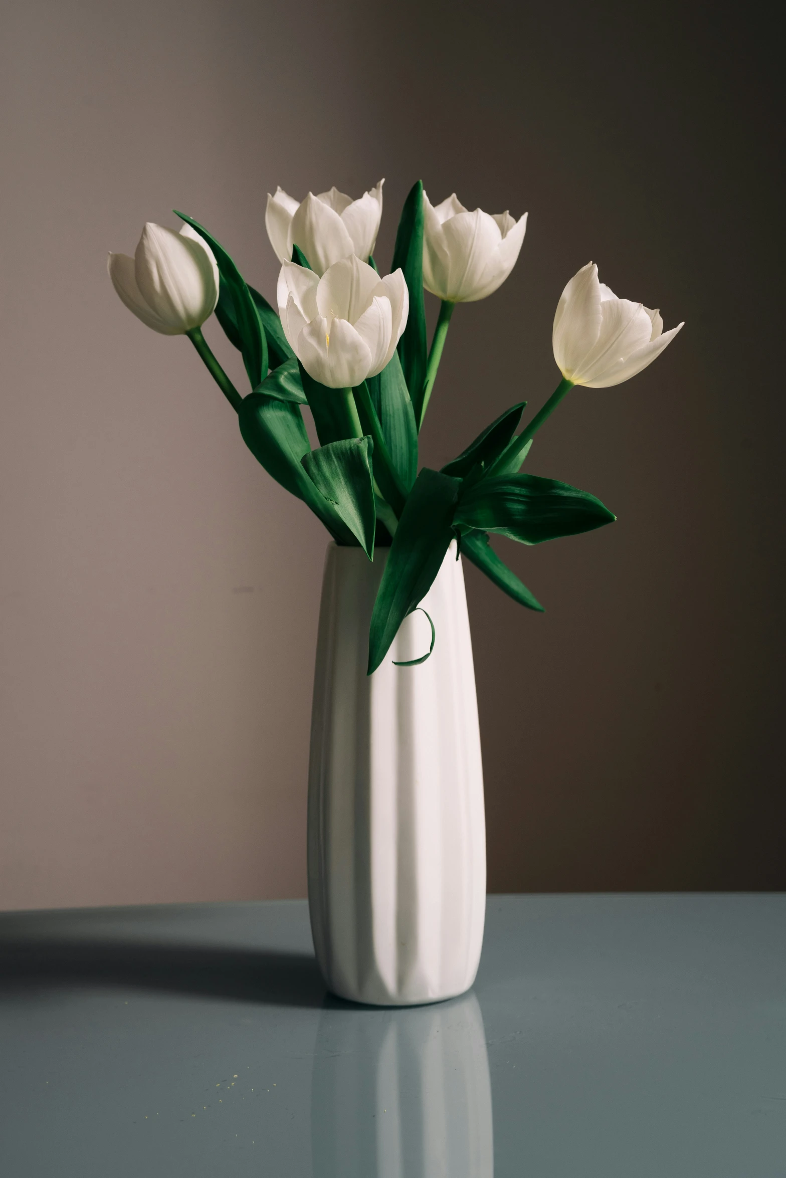 a white vase with flowers on a table