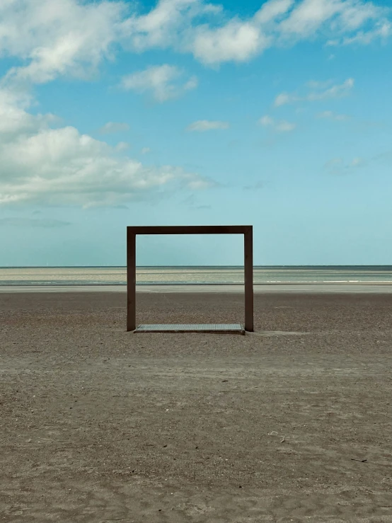 a wooden box stands in the sand at the beach