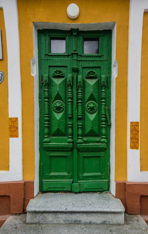 a green door sits in front of a yellow wall