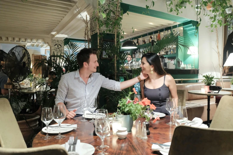 a man and woman smiling at each other while sitting at a table