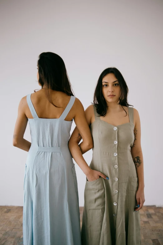 two women are looking back at soing while standing in front of a white wall