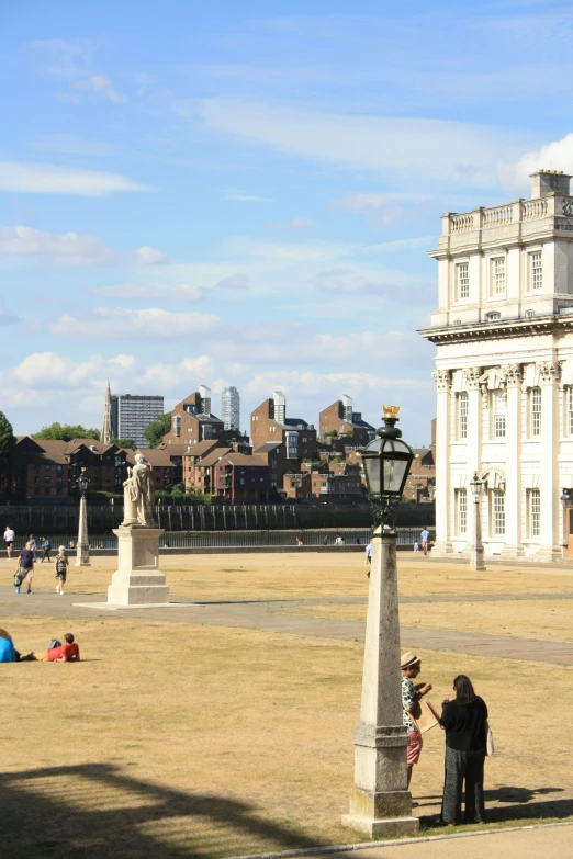 two people stand by the tall pillar in a square