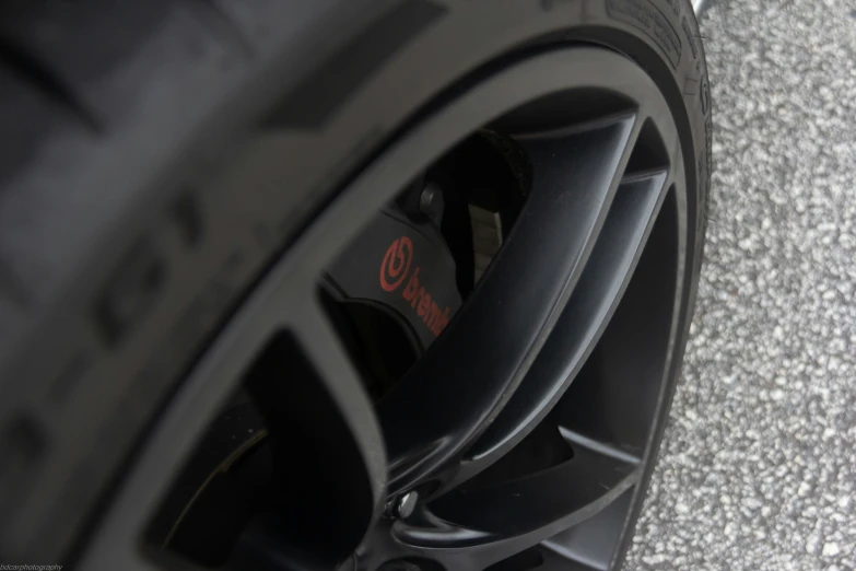 a wheel with a small red and black emblem sits on the cement