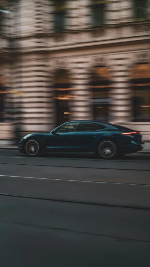 a blue sports car is driving past some tall buildings