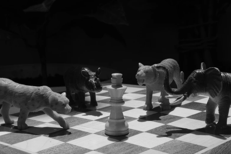 small plastic animals are standing around chess board