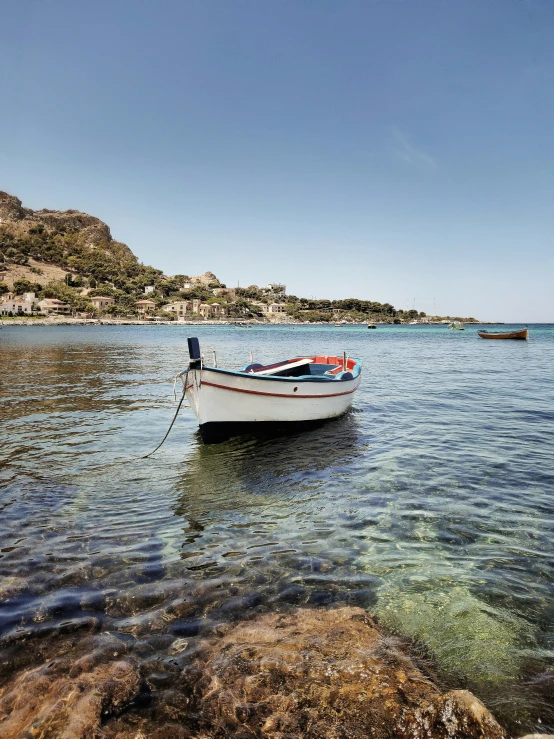 boat sitting on the shore in front of rocks