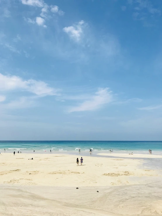 many people on the beach near some very pretty water