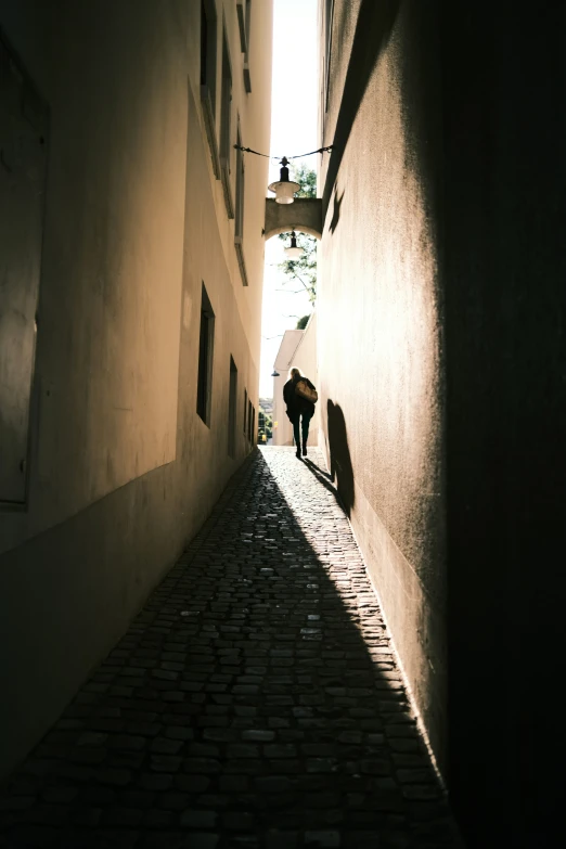 a lone man stands in the shadows on an alley