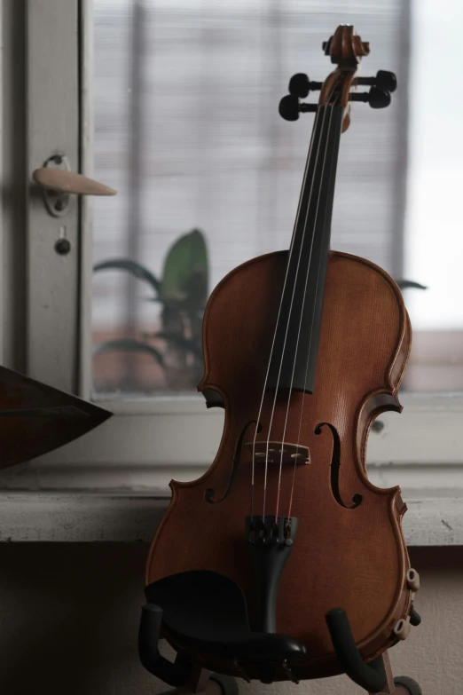 a violin on wheels sits in front of a window