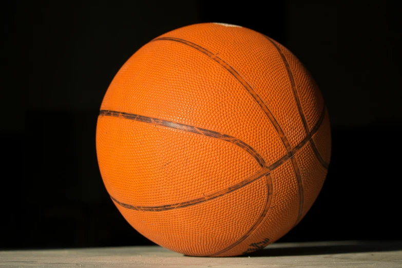 a basketball on a black background sitting on a wooden table