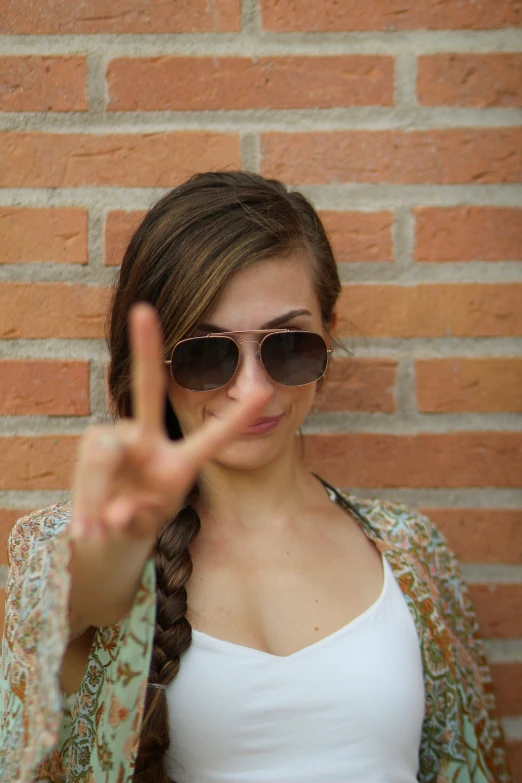 a girl with a id and sunglasses making the peace sign