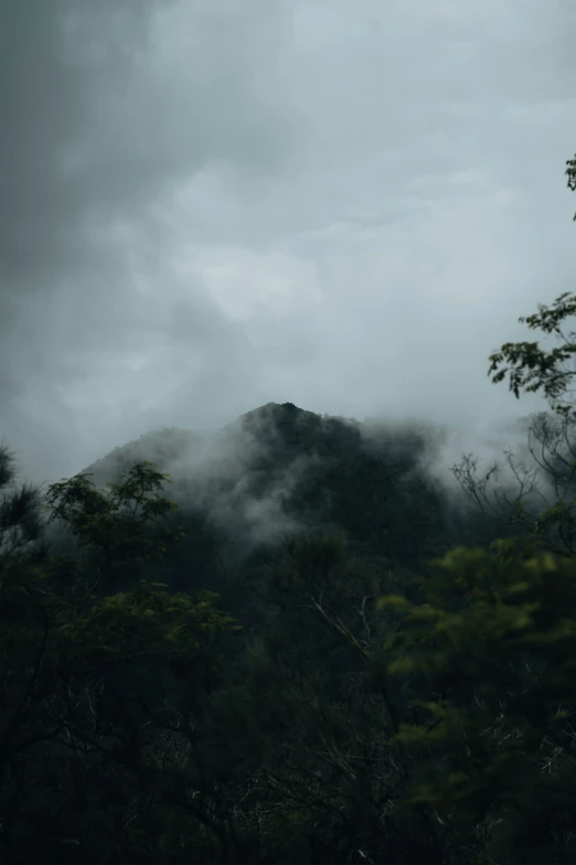 a couple of hills covered in clouds and trees