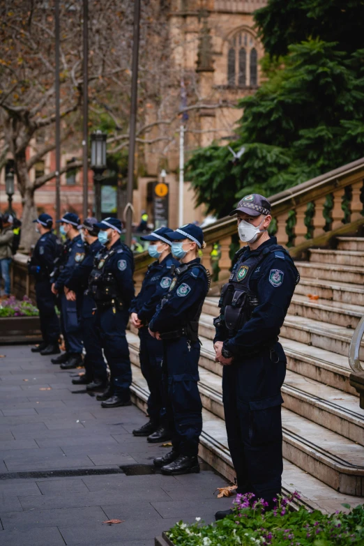 police standing in front of steps, all wearing facemasks