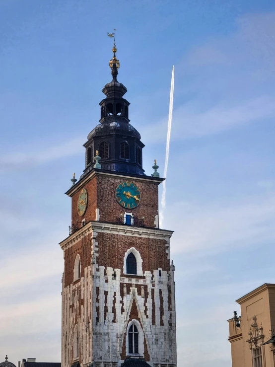 a clock tower with a steeple and weather vane in a city square