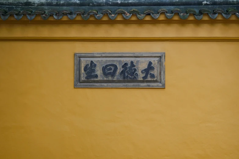 a painting on a yellow wall with some chinese characters on the wall