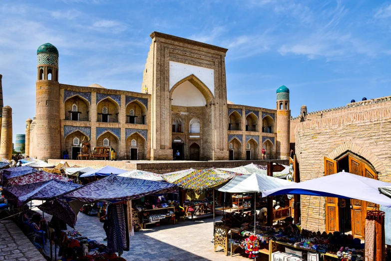 a market in front of a stone building with large windows