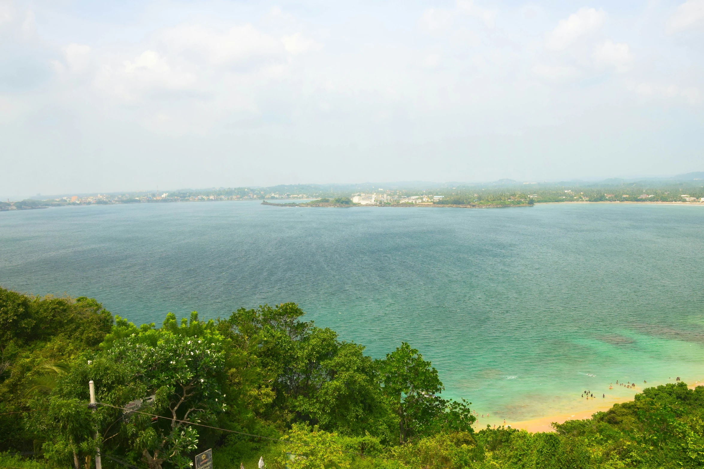 a beach near a wooded, wooded area with clear blue water