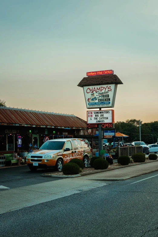 cars parked in front of a resturant with a lit sign above
