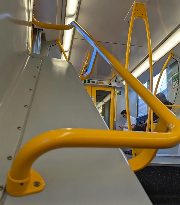 people sitting on a subway train with yellow rails