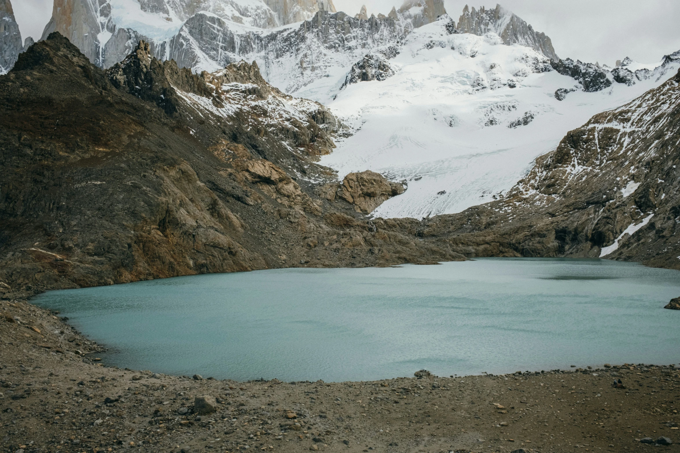 the snow covered mountain peaks are above a small lake