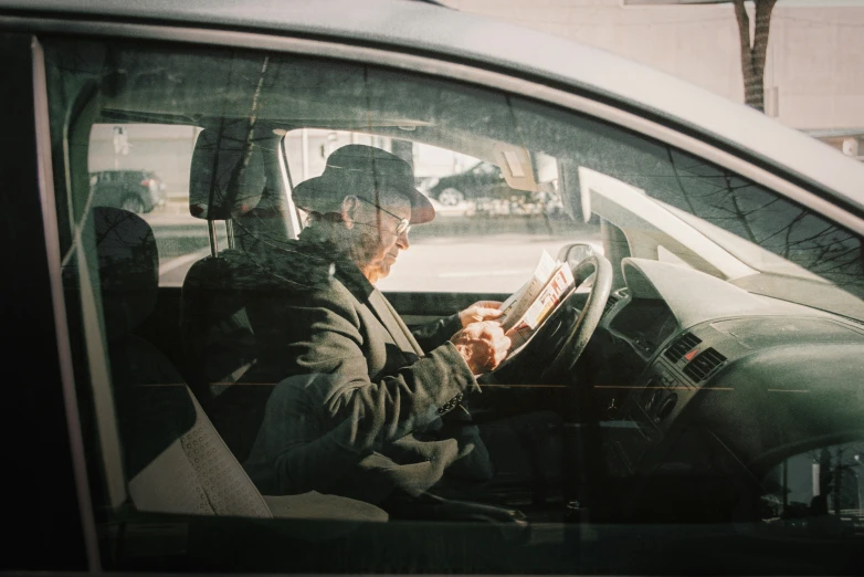 a man in a car with a phone and other items in his hands