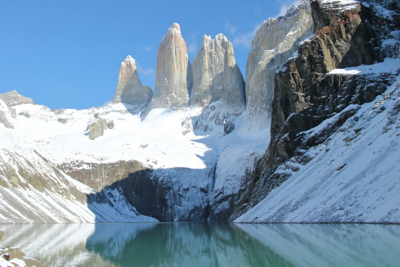 two mountain peaks near the shore and water in winter