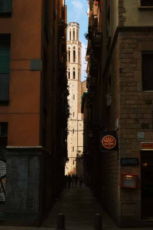 a narrow alley between two buildings with a clock tower in the distance