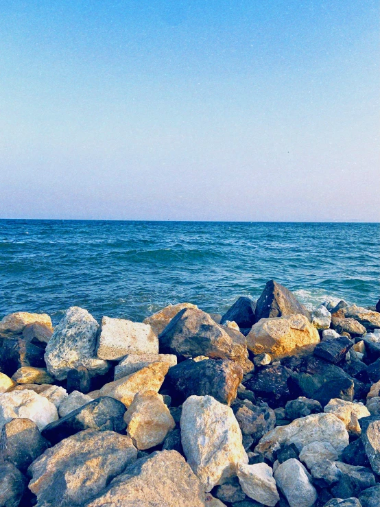 a person walking by the water at a rocky shore