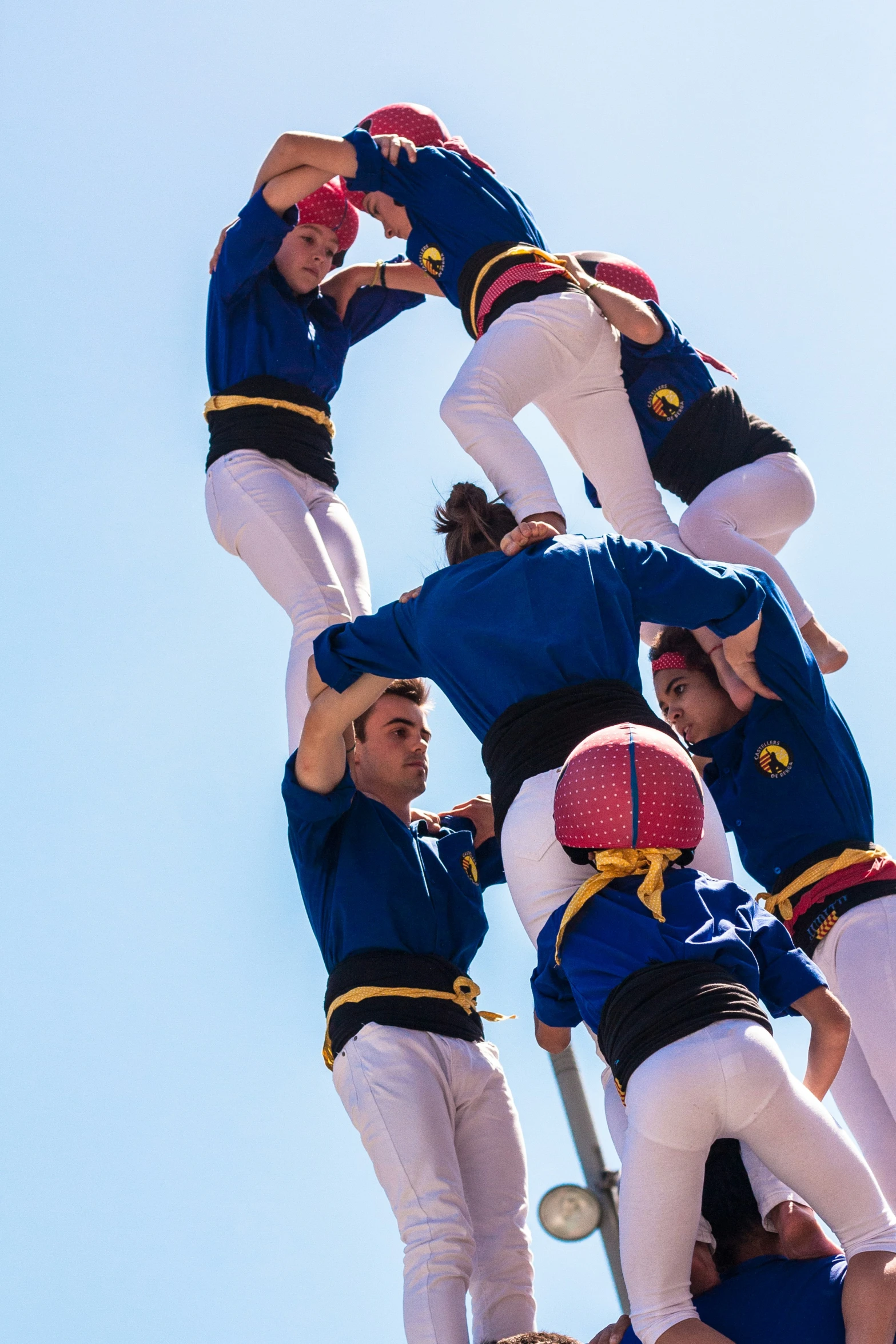 several guys balancing themselves on top of a pole