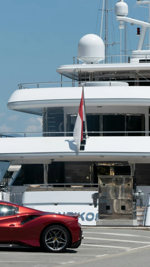 a sports car sits parked in front of a yacht