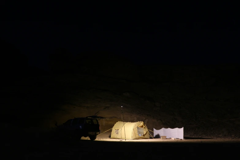 two tents pitched on the side of a hillside at night