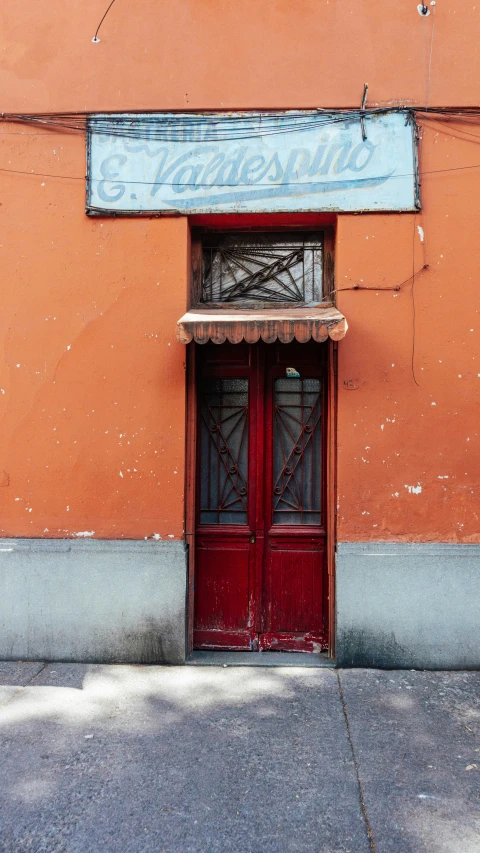 an empty street with the door in red painted brick and a faded sign