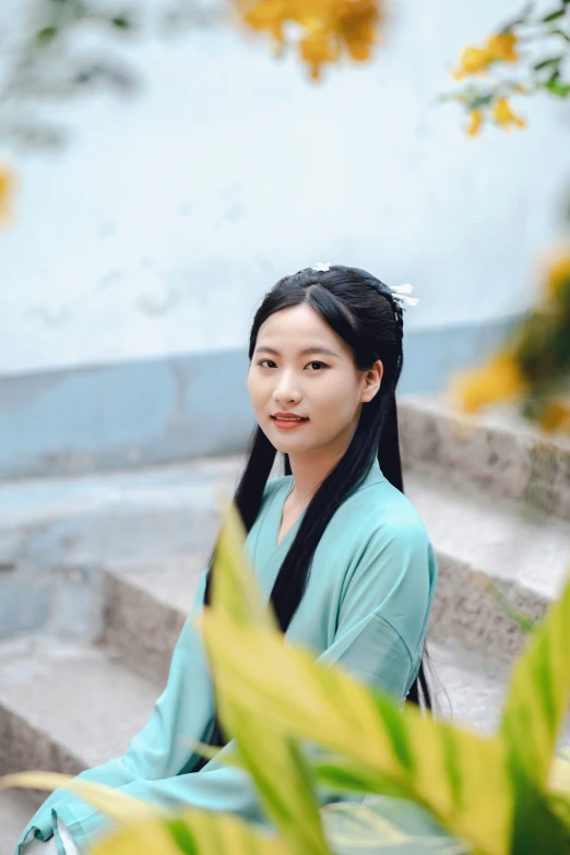 asian lady in blue dress sitting on steps by flowers