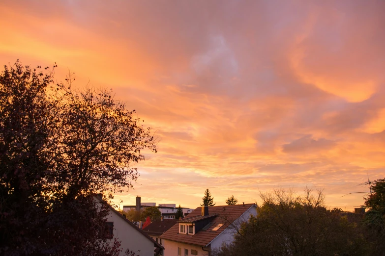 some houses under a bright orange sky and clouds