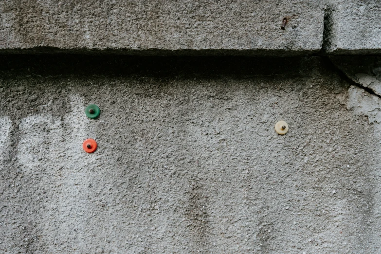 a concrete wall with small multicolored ons attached to it