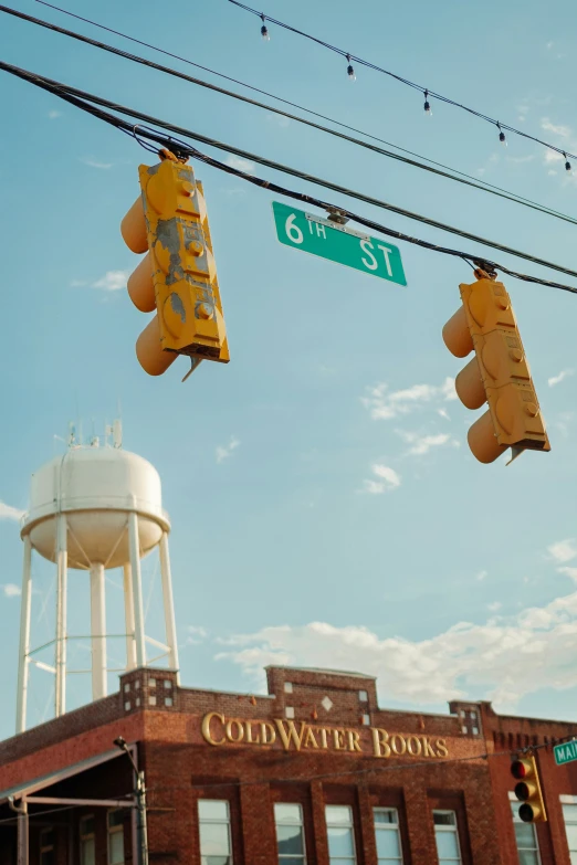 two traffic lights hang over an intersection in front of a water tower