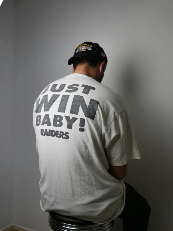 a man sitting down wearing a shirt that says just win baby