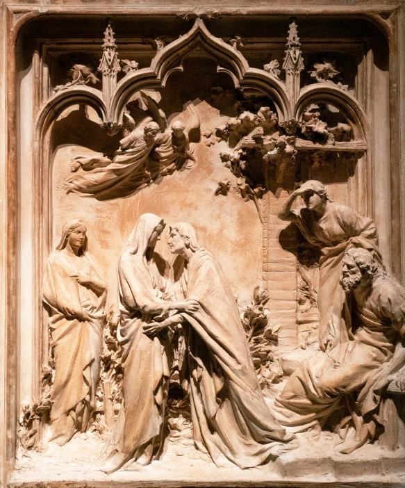 a carving in a church, depicting three women on the ground