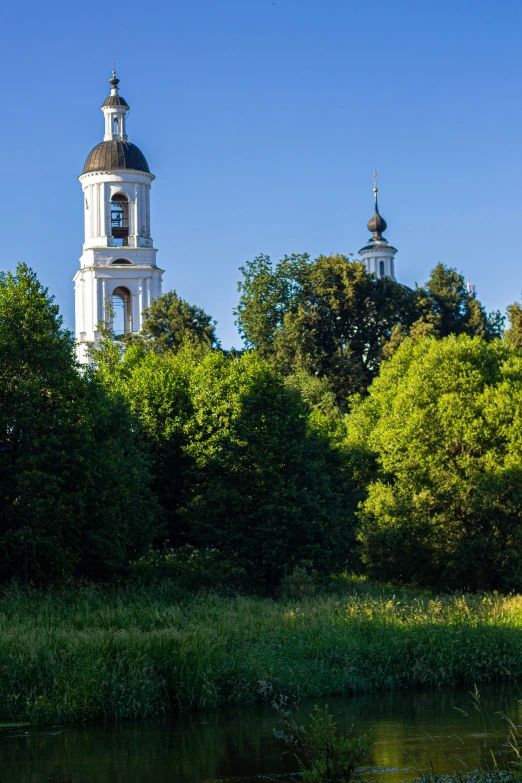 the white building is next to some trees and water