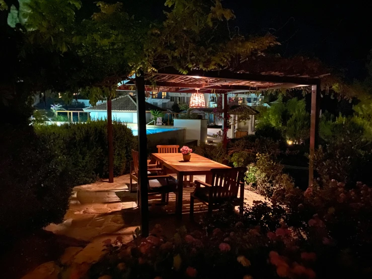 a table and chairs in front of a gazebo at night