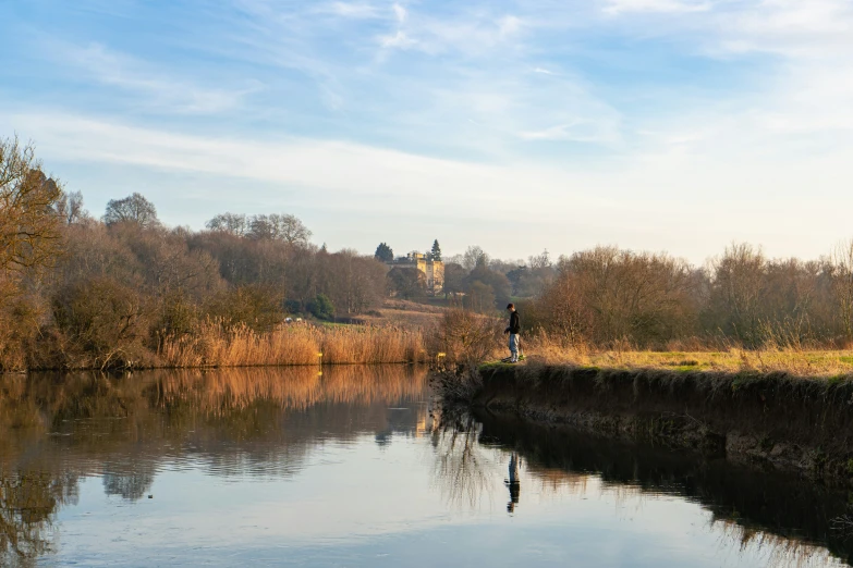 the person is fishing from a rocky bank by the lake