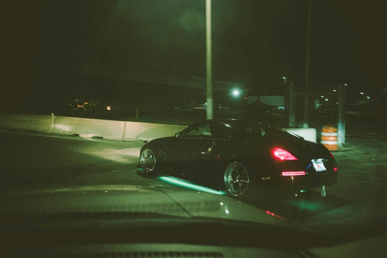 some cars on a dark road by an orange cone