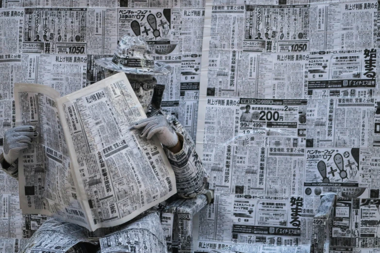 a statue holding a newspaper next to a wall covered in news paper