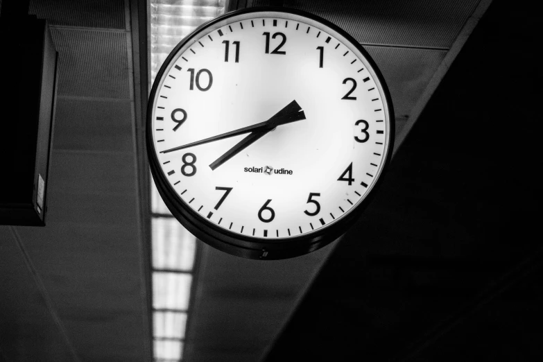 a wall clock hanging from the ceiling with one hand