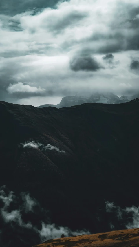 a grassy hillside beneath a cloudy sky covered with clouds