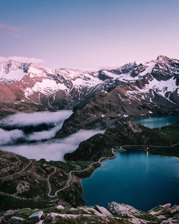 a lake nestled on top of a mountain surrounded by clouds