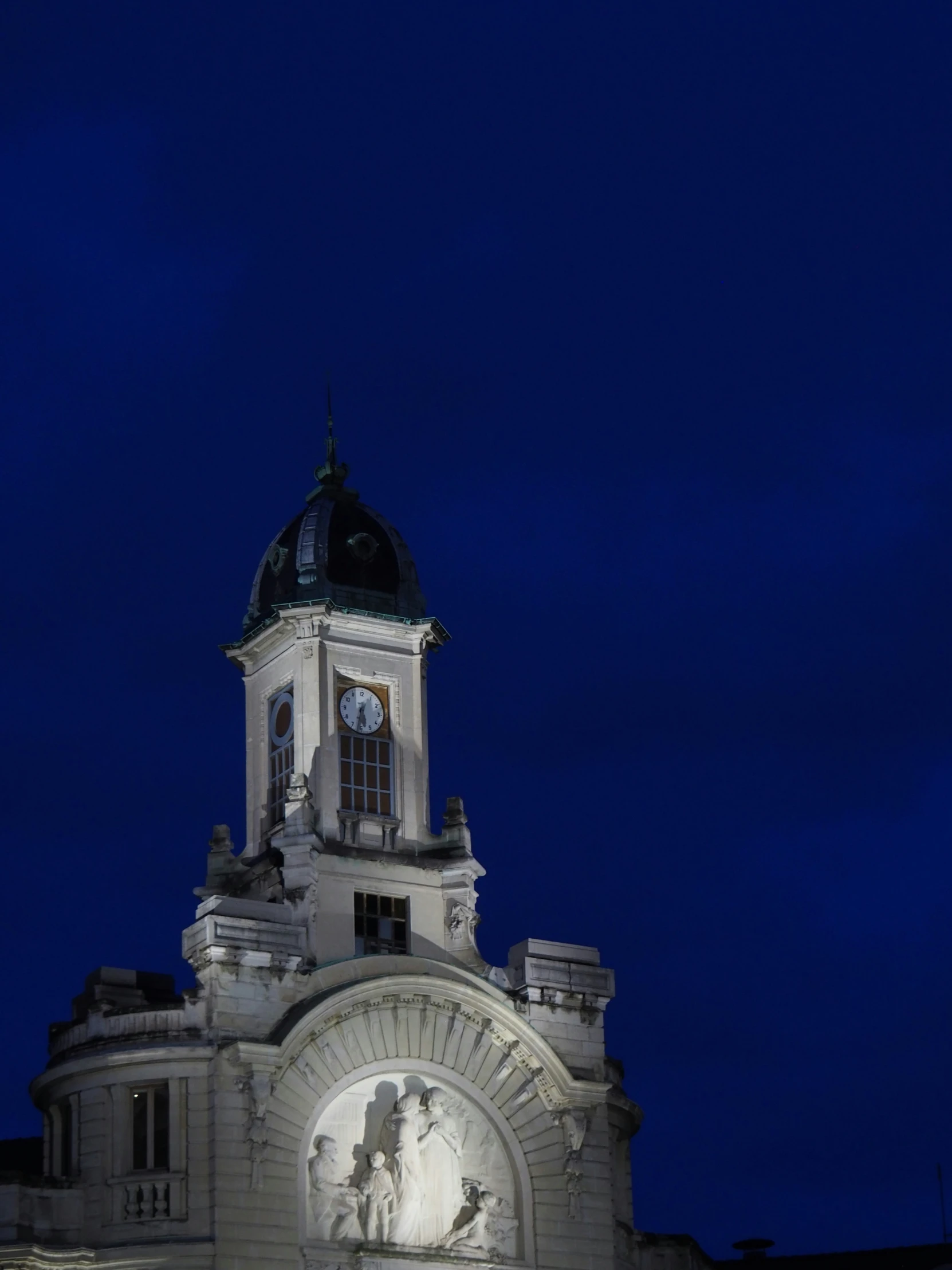 the clock tower on top of the building lit up at night