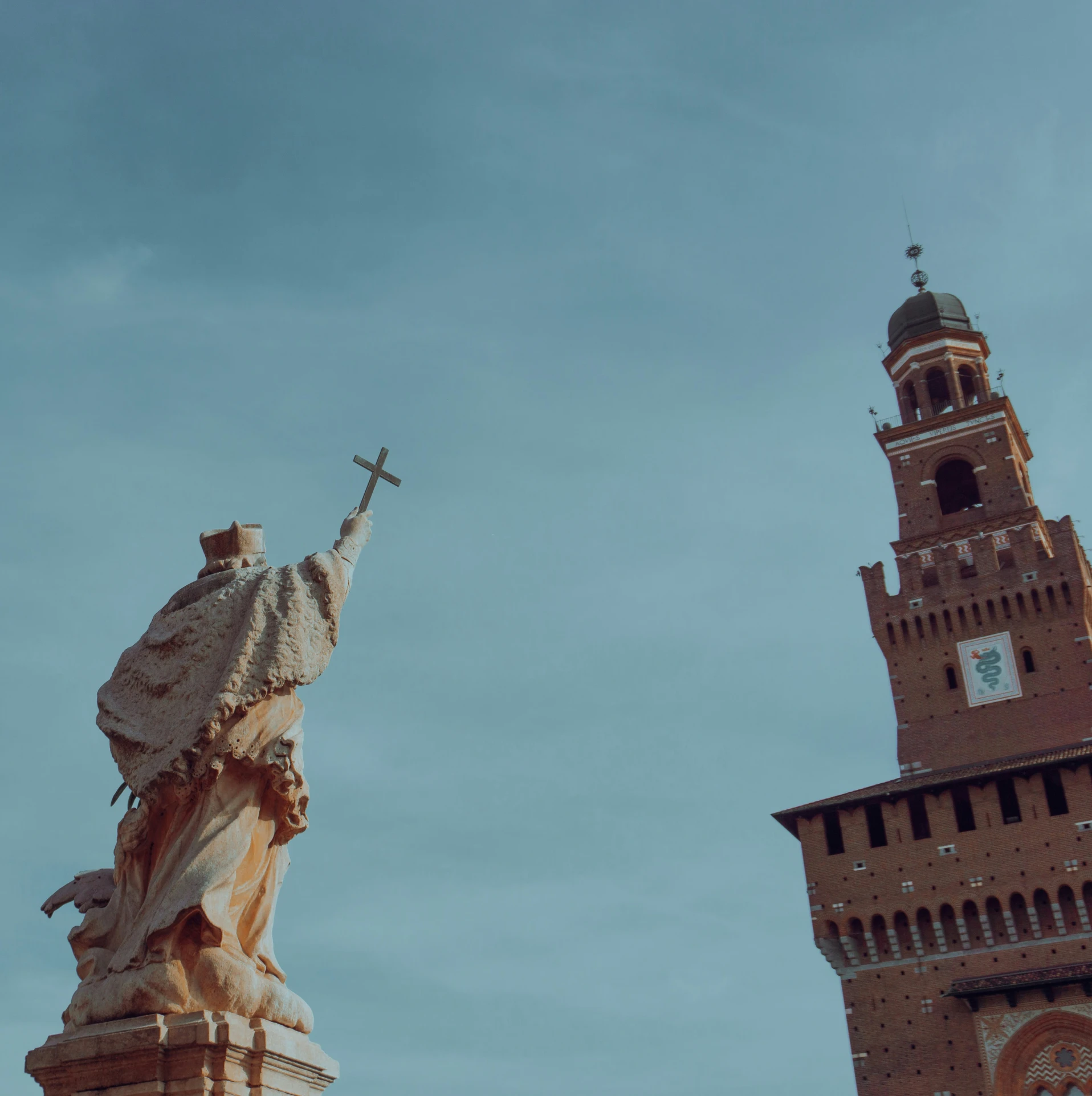 a statue with a cross and a church tower